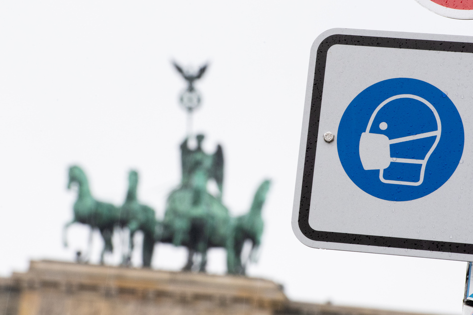 Berlin: Am Pariser Platz vor dem Brandenburger Tor weist ein Hinweisschild auf die Maskenpflicht hin.
