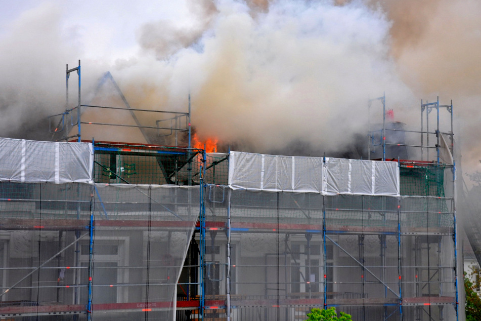 Das Dach des Mehrfamilienhauses steht in Flammen.