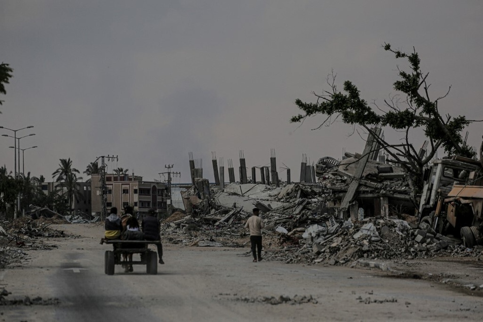 Palestinians ride a horse-drawn carriage past destroyed buildings in Khan Younis city in the southern Gaza Strip.