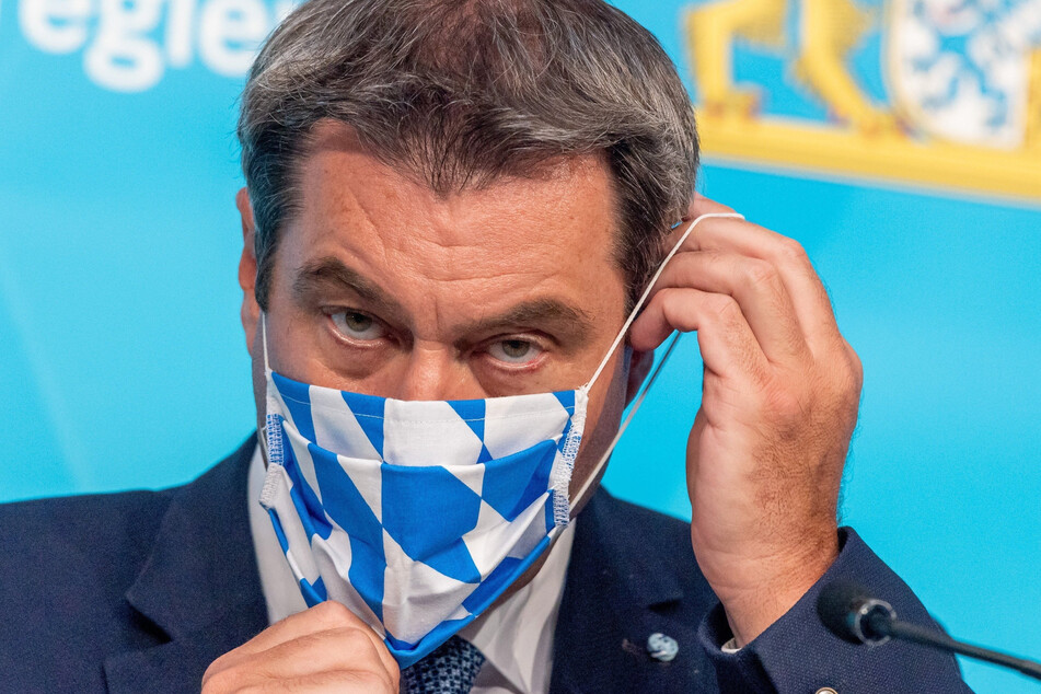 Markus Söder (CSU), Ministerpräsident von Bayern, setzt sich nach einer Pressekonferenz zur aktuelle Entwicklungen an den Corona-Teststationen für Reiserückkehrer seine Gesichtsmaske auf.