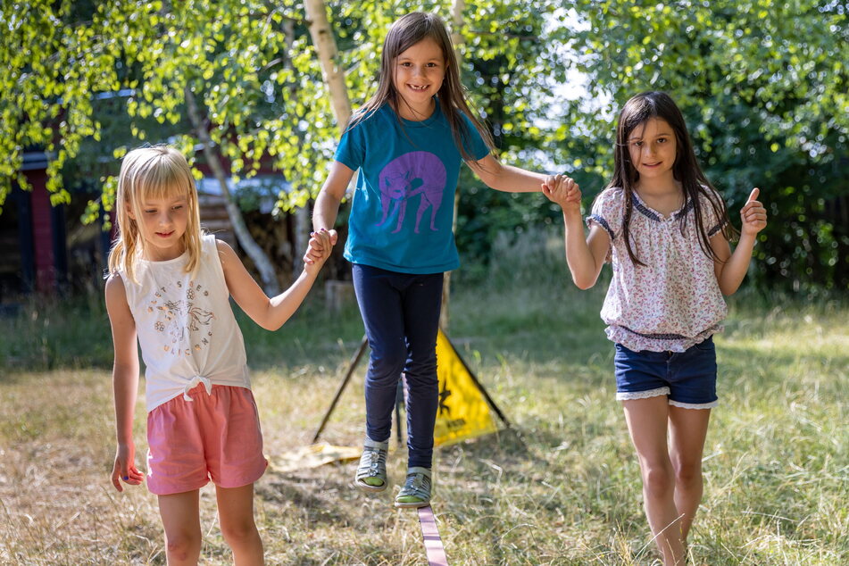 Spaß mit dem Lauf-Band beim Walden e. V.: Zoe (6) übt mit Matilda (7, l.) und Luca (9) über eine Slackline zu balancieren.