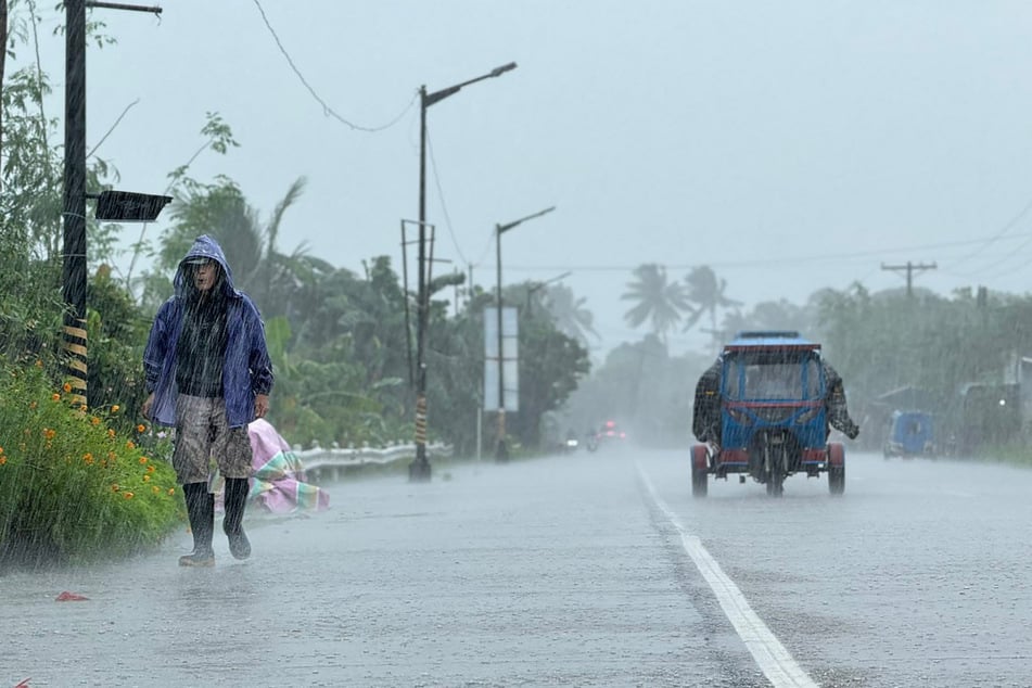 A man walks along a road amid heavy rain due to weather patterns from Super Typhoon Ragasa in Lal-lo town, Cagayan province, Philippines, on September 22, 2025.