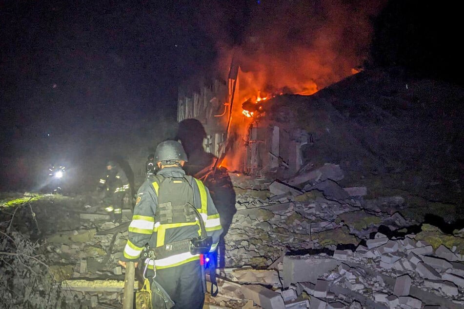 Feuerwehrleute löschen das Feuer in einem Gebäude nach einem russischen Angriff in Sumy.