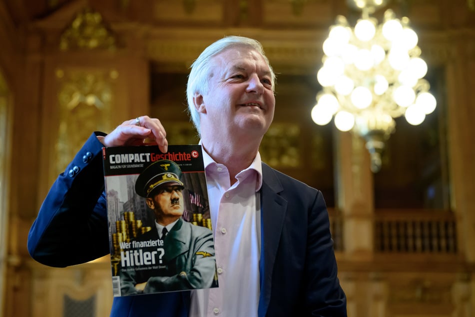 "Compact"-Chefredakteur Jürgen Elsässer (68) mit einer Ausgabe seines Magazins "Compact Geschichte". Am Mittwoch wurde das Verfahren gegen das rechtsextreme Blatt fortgesetzt.