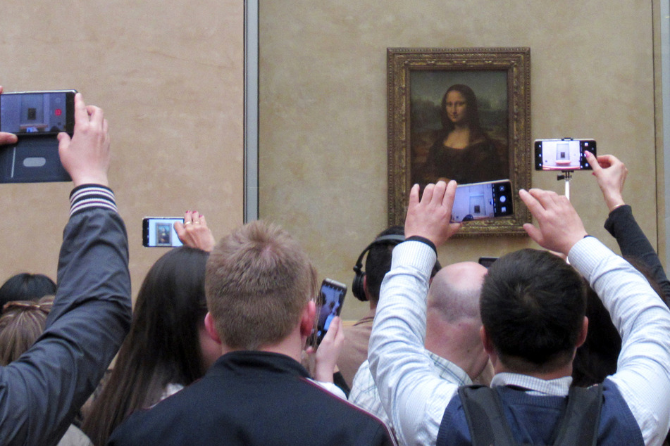 Mann verkleidet sich als Rollstuhl-fahrende Frau und bewirft Mona Lisa mit einer Torte