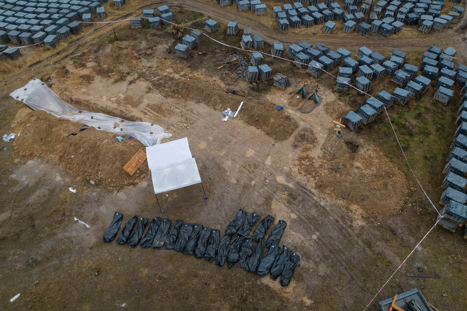 Schwarze Plastiksäcke mit Leichen, die aus einem Massengrab exhumiert wurden, liegen aufgereiht in Butscha.