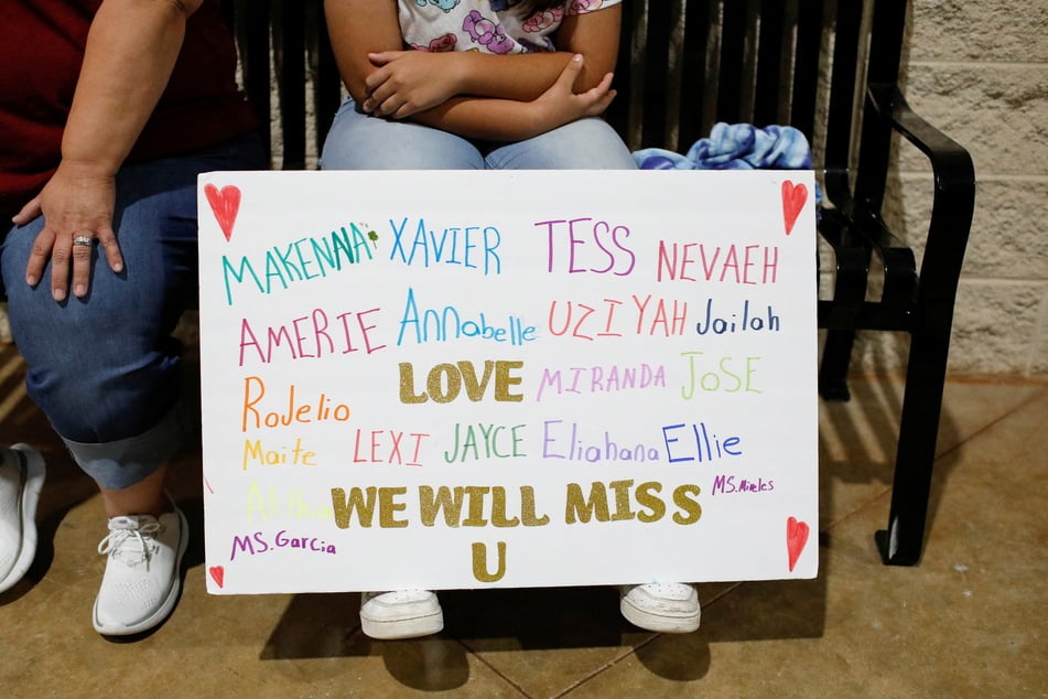 A mourner holds a sign with the names of the victims of the Robb Elementary school shooting during a vigil at Uvalde County Fairplex Arena on Wednesday.