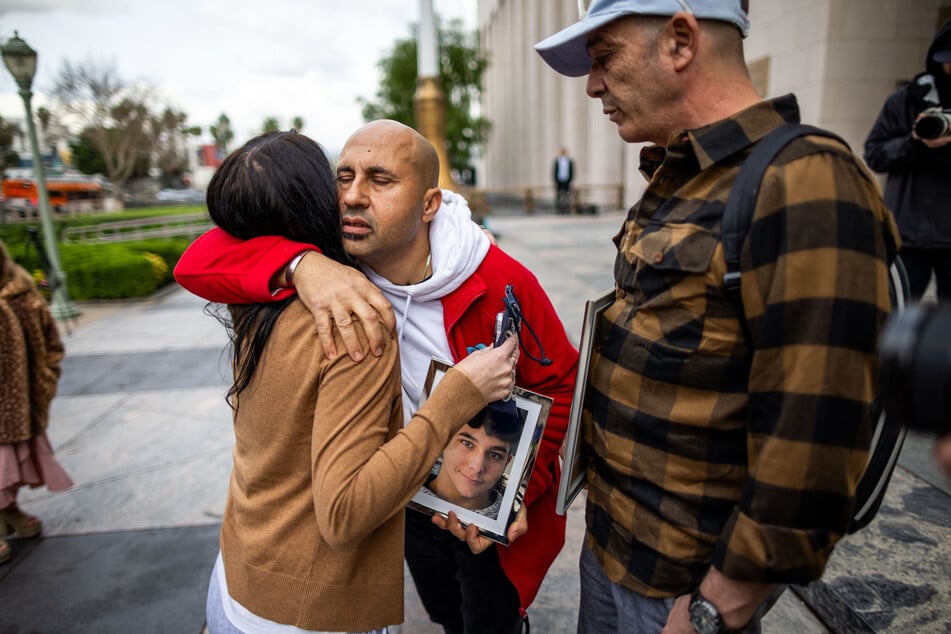 People holding photos of their children embrace outside the Los Angeles Superior Court on February 11, 2026.