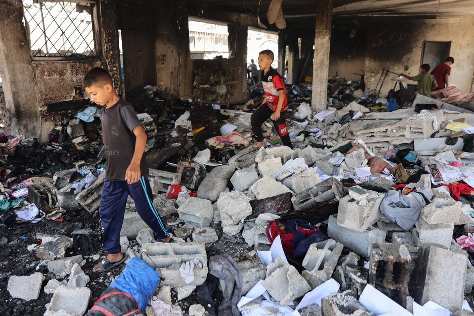 Children walk over debris at Mustafa Hafez school following an overnight Israeli strike in Gaza City on July 3, 2025.