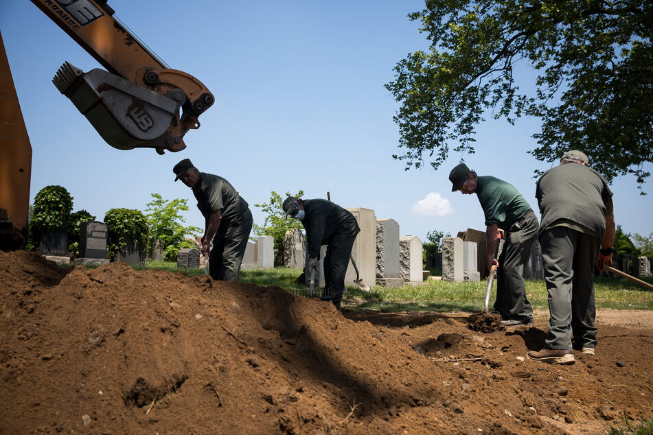 USA, New York: Mitarbeiter des Friedhofs "Calvary Cemetery" arbeiten während der Corona-Pandemie an einem Grab.