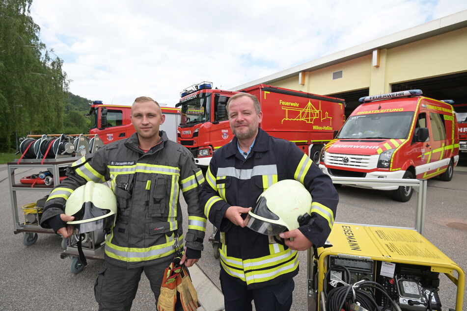 Björn Jerzembek-Preinl (29, l.) und Christian Schwieder (40) von der Freiwilligen Feuerwehr Wilkau-Haßlau stehen vor den einsatzbereiten Fahrzeugen.