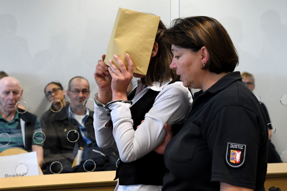 Mit verdecktem Gesicht wird die Angeklagte in den Gerichtssaal geführt.