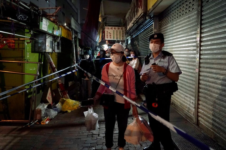 Eine Bewohnerin mit Mund-Nasen-Schutz wartet im gesperrten Bereich des Bezirks Sham Shui Po darauf, nach Hause zu gehen.