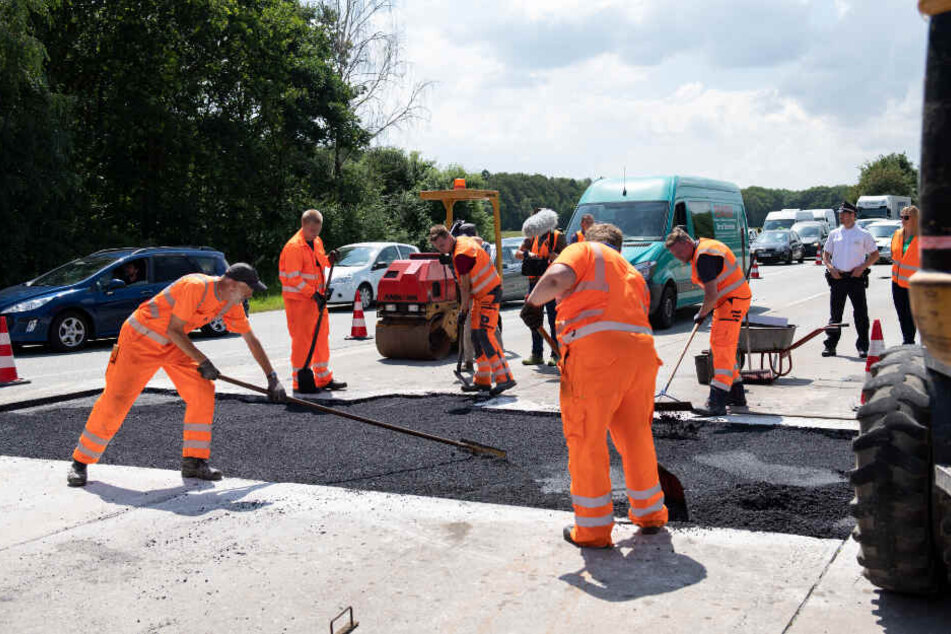 Arbeiter ziehen den neuen Asphalt auf der A1 bei Lübeck glatt.