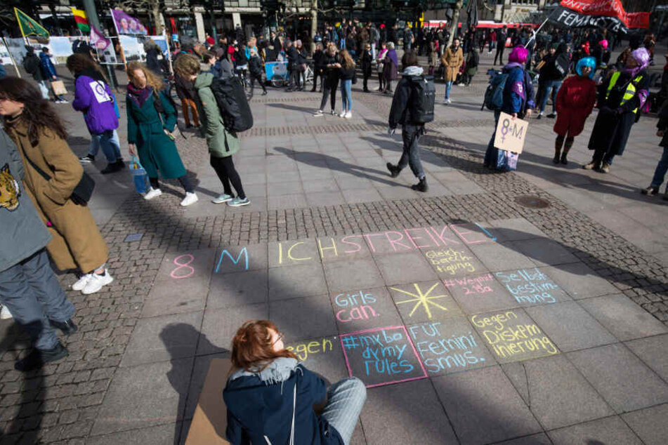 Am Rathausmarkt schreiben Frauen ihre Botschaften mit Kreide auf den Boden.
