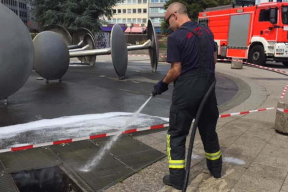 Die Feuerwehr spült den Restschaum im Brunnen weg.