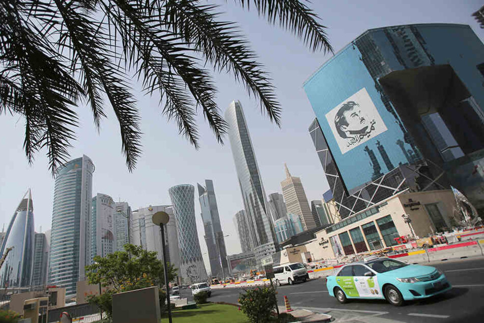 Ein Taxi passiert ein Gebäude mit einem Bild des Emirs von Katar, Sheikh Tamim bin Hamad Al Thani.