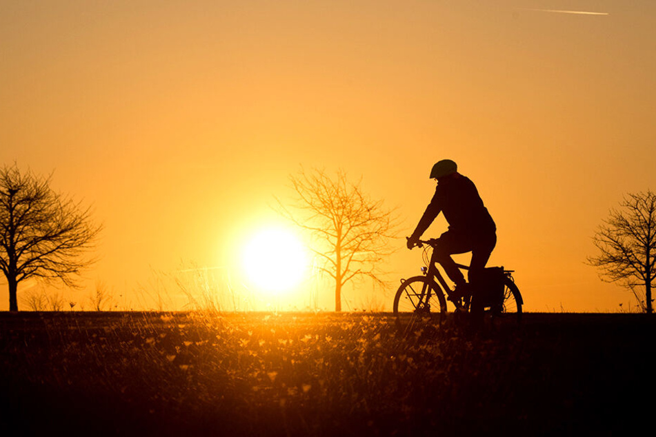 Ein Fahrradfahrer radelt vor einem malerischen HIntergrund.