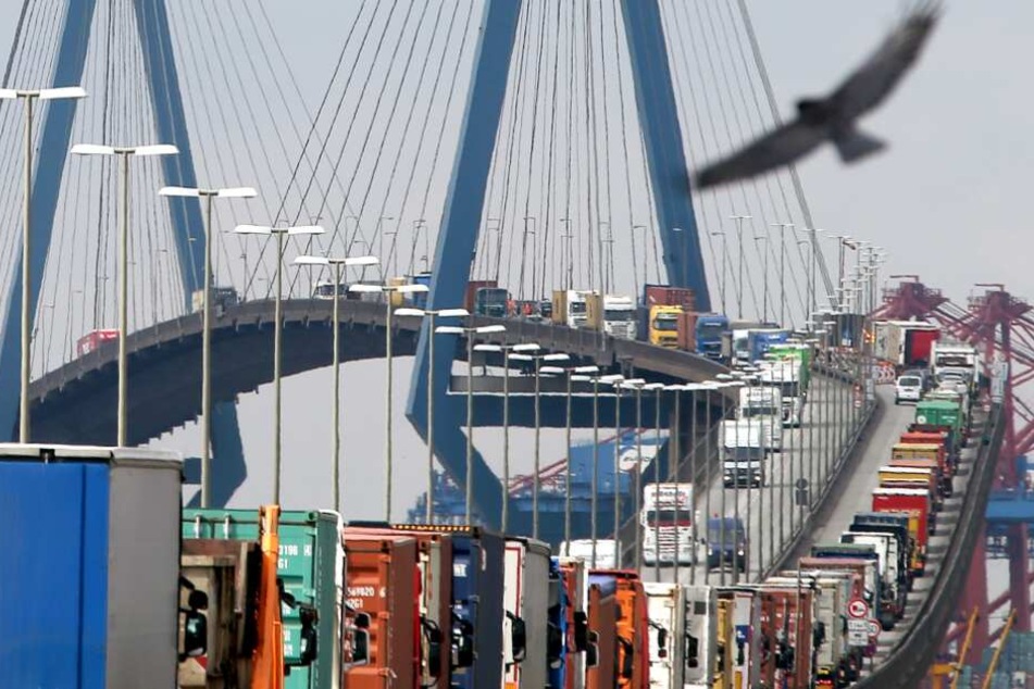 Mit Containern beladene Lastwagen stauen sich auf der Köhlbrandbrücke im Hafen.