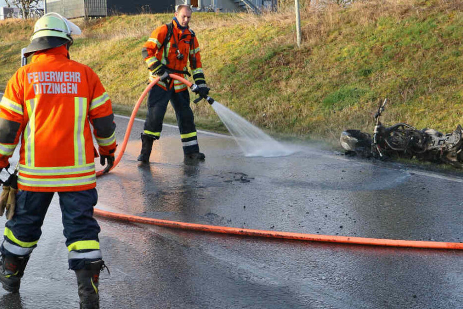 Feuerwehrmänner spritzen die Straße mit Wasser ab.