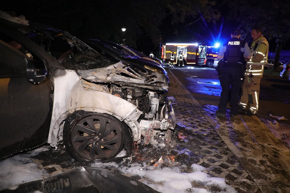 Einsatzkräfte auf dem Parkplatz an der Ziegelstraße, vor dem völlig verschmorten Honda.