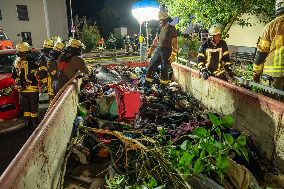 Feuerwehrleute räumten den Keller in Handarbeit und sammelten alles in einer Mulde vor dem Haus.