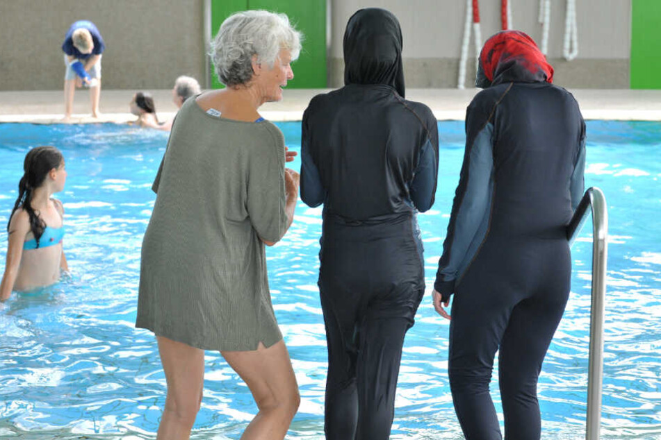 Zwei Muslima stehen im Burkini vor einem Schwimmbecken (Symbolfoto).