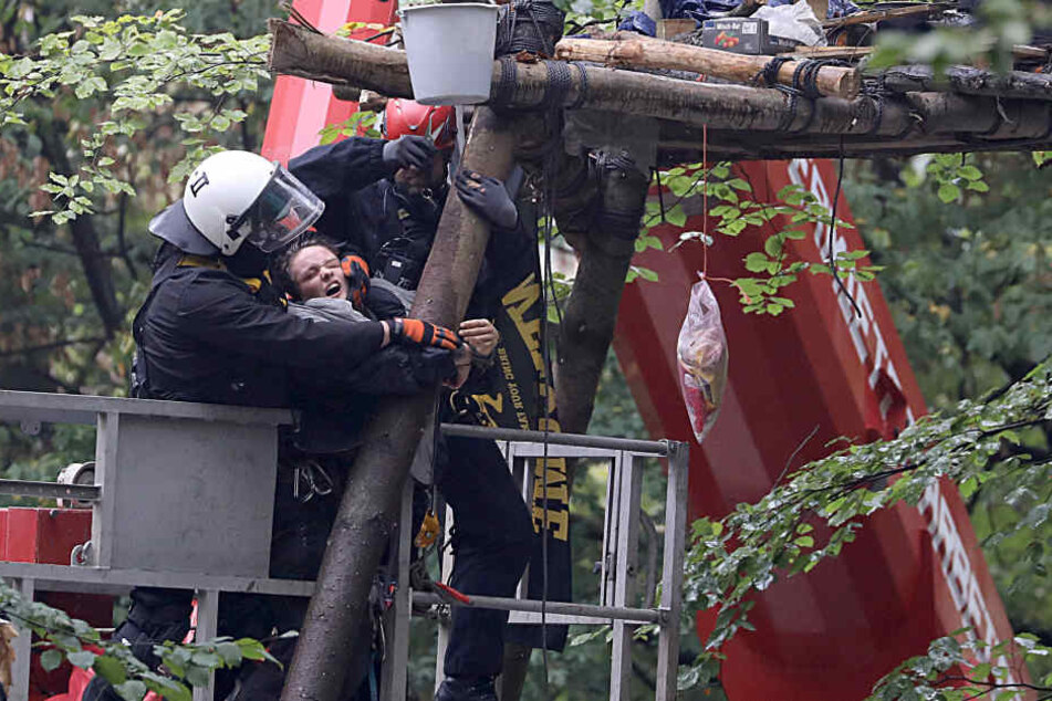 Polizisten und eine Aktivistin bei der Räumung eines Baumhauses.