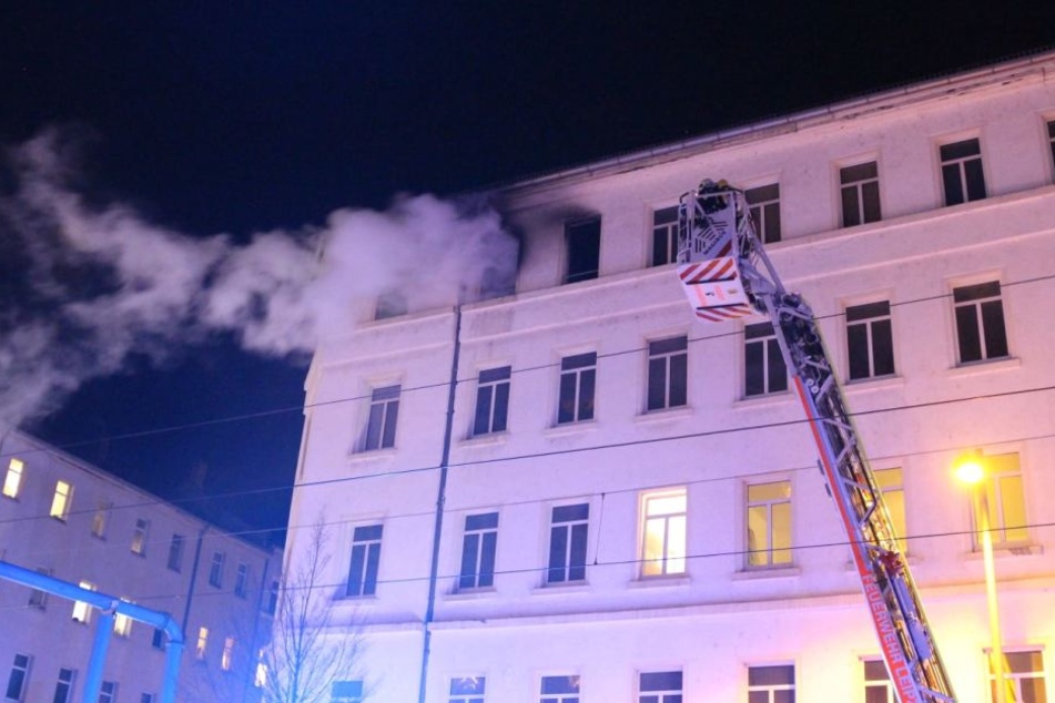 Kameraden der Leipziger Feuerwehr werden mit einer Drehleiter an der Fassade des Mehrfamilienhauses in die vierte Etage gefahren. Dort ist am Mittwoch ein Brand ausgebrochen.