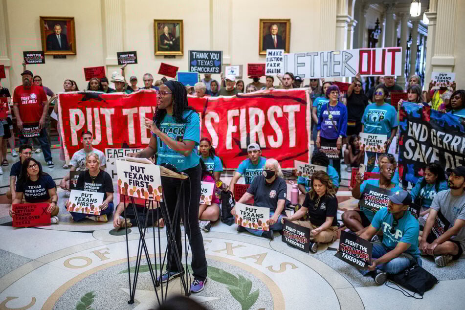 A demonstrator speaks during a protest on the floor of the Texas Capitol rotunda as Democratic lawmakers, who left the state to deny Republicans the opportunity to redraw the state's 38 congressional districts, begin returning on August 20, 2025.