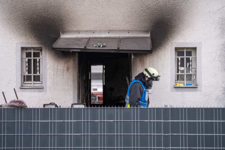 Ein Feuerwehrmann mit Atemschutz-Ausrüstung verlässt das Haus, in dem fünf Menschen bei einem Brand ums Leben kamen.