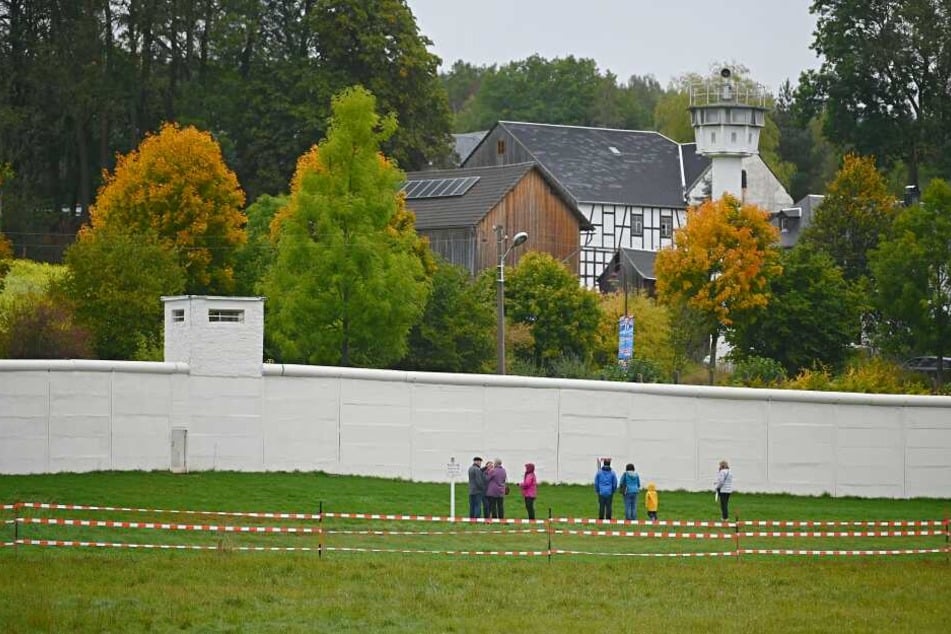 Besucher stehen vor einem Teil der ehemaligen Mauer. Im ehemals geteilten Dorf Mödlareuth wurde am Donnertag eine Einheitsfeier abgehalten.