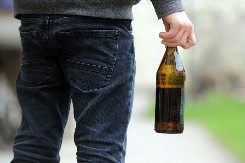 Ein Jugendlicher hält eine Flasche Bier in der Hand.