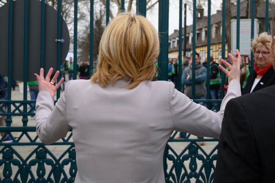 Julia Klöckner (CDU), Bundesministerin für Ernährung, Landwirtschaft und Verbraucherschutz geht auf Demonstranten zu, die hinter einem Gittertor stehen.