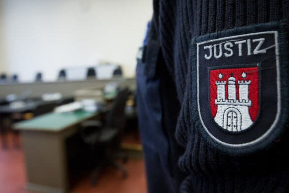 Ein Hamburger Justizbeamter steht vor einer Verhandlung im Gerichtssaal.