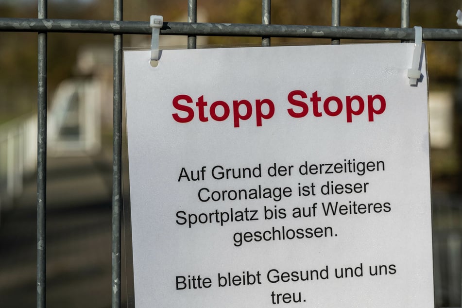 Ein Schild hängt am Zaun eines Fußballplatzes.