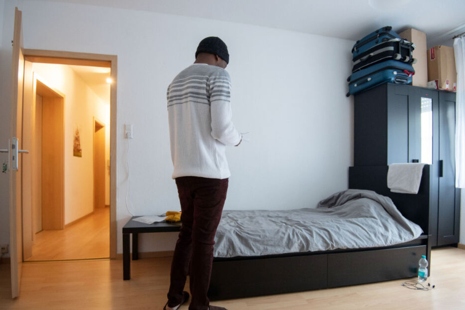 Ein Bewohner einer Männerschutzwohnung betrachtet in seinem Zimmer Unterlagen.
