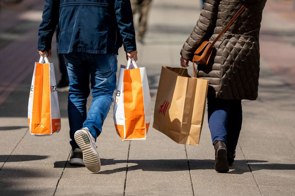 Passanten halten Einkaufstüten in den Händen. Wegen sinkenden Infektionszahlen kann in einigen Städten, nach vorheriger Terminvereinbarung, wieder geshoppt werden. (Symbolbild)