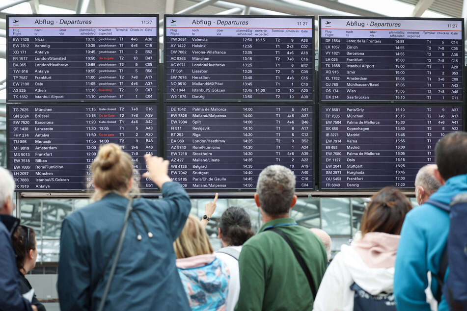 Flugreisende stehen unter den Anzeigetafeln in Terminal 1 am Airport Hamburg. (Archivbild)