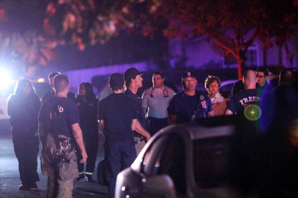 Einsatzkräfte von Polizei und Feuerwehr stehen auf einer Straße. Vier Menschen sind im US-Staat Kalifornien in einem Garten von einem Unbekannten erschossen worden.
