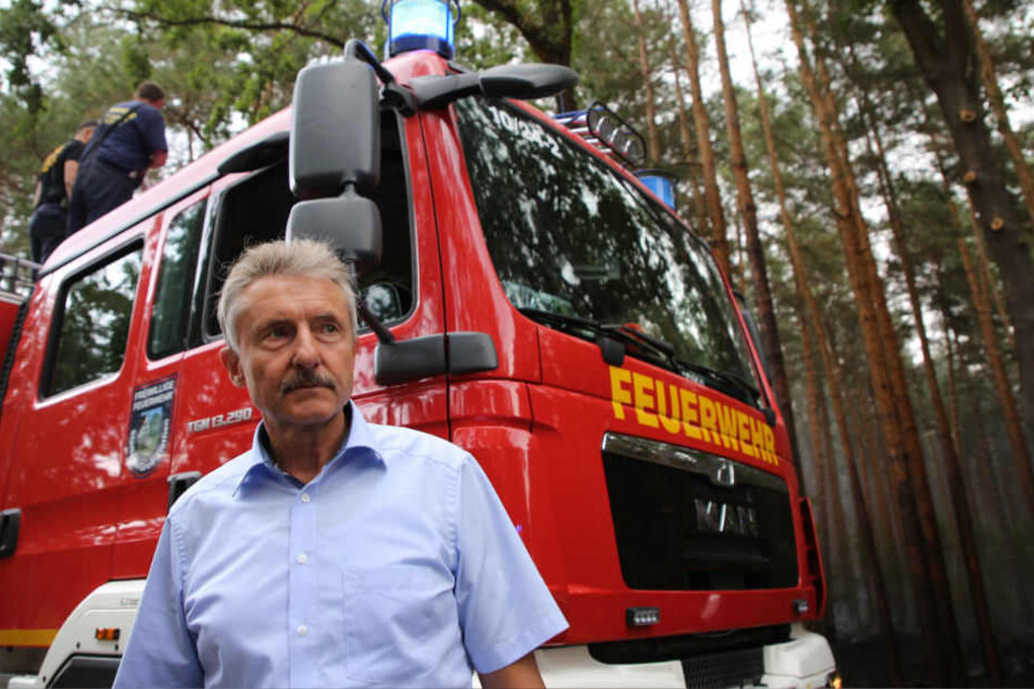 Brandenburgs Innenminister Karl-Heinz Schröter (SPD) informiert sich bei der Feuerwehr über die Situation bei einem Waldbrand.