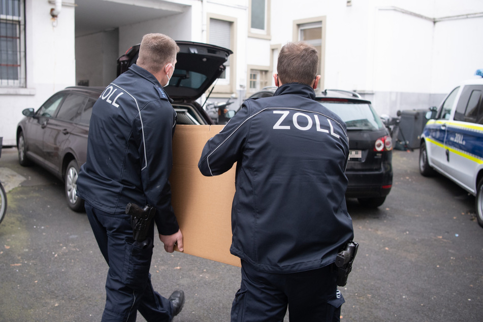 Kisten mit Beweismaterial tragen Beamte des Zolls bei der Razzia aus einem Bürogebäude in Frankfurt.