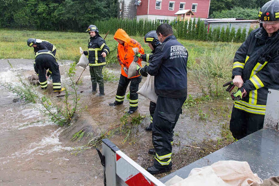 Feuerwehrleute schichten im Suhler Stadtteil Neundorf Sandsäcke auf.