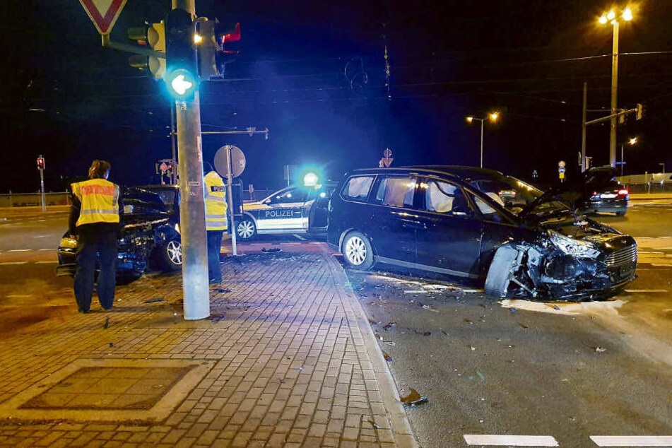 Polizisten stehen vor dem demolierten blauen Fiat (l.) des Unfallfahrers. In dem Wagen ließ er seine verletzte Familie zurück.
