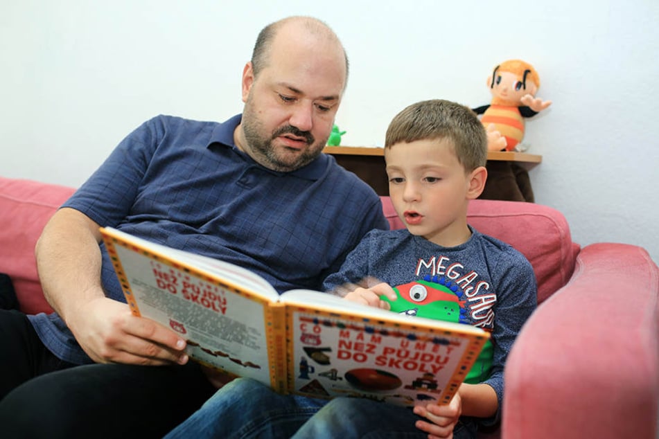 Petr Cizmar schaut mit seinem Sohn ein Kinderbuch an. David kann heute schon ein bisschen lesen - im August wurde er in Dresden eingeschult.