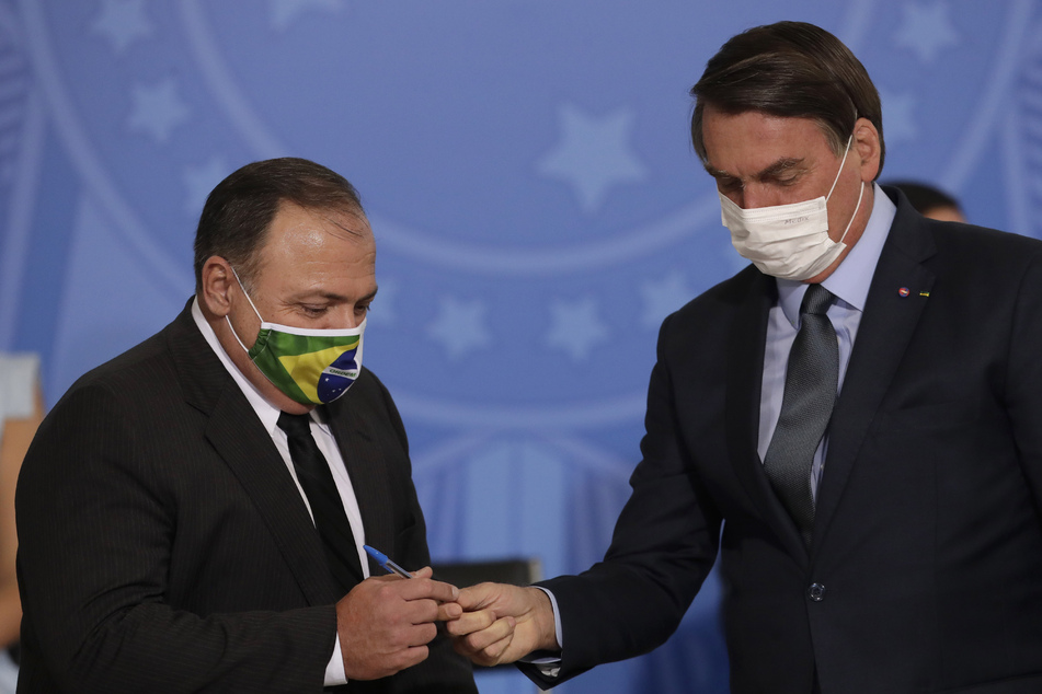 Brasiliens Präsident Jair Bolsonaro (r.) überreicht seinem neuen Gesundheitsminister Eduardo Pazuelo einen Stift.