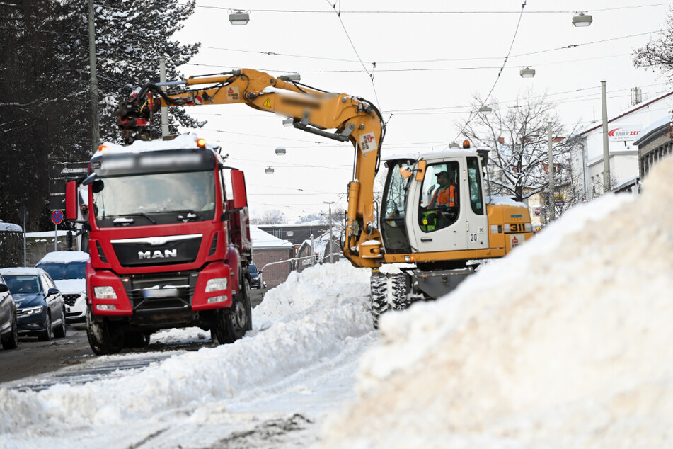 Mit einem Bagger werden in Kassel die Schneemengen von den Straßenbahngleisen entfernt.