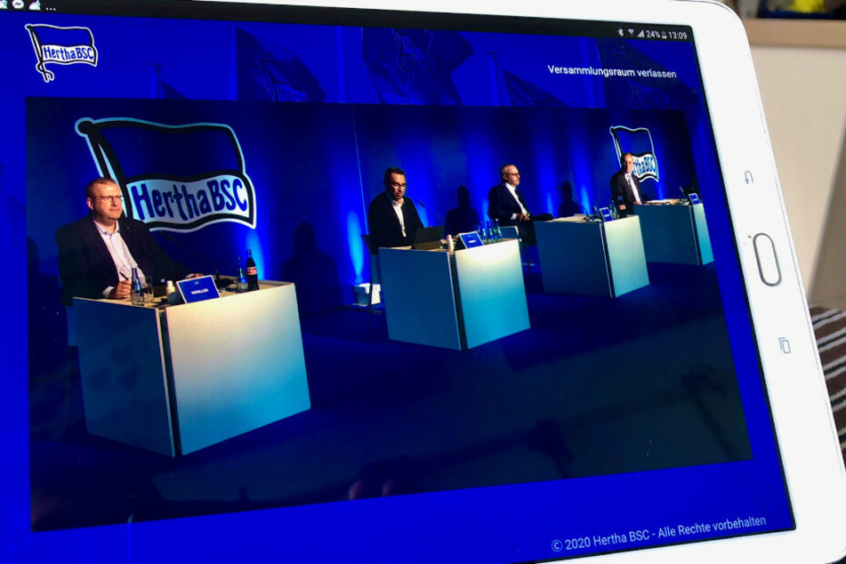 Das Podium mit Herthas Finanz-Geschäftsführer Ingo Schiller (l) und Hertha-Manager Michael Preetz (2.v.l.), ist bei der digitalen Mitgliederversammlung von Hertha BSC auf einem Tablet zu sehen.