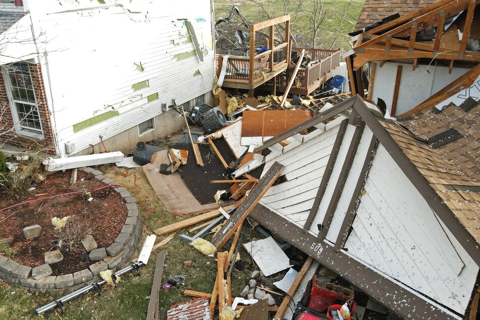 Debris lies around a damaged house the morning of March 15, 2025, after a tornado touched down in Florissant, Missouri.