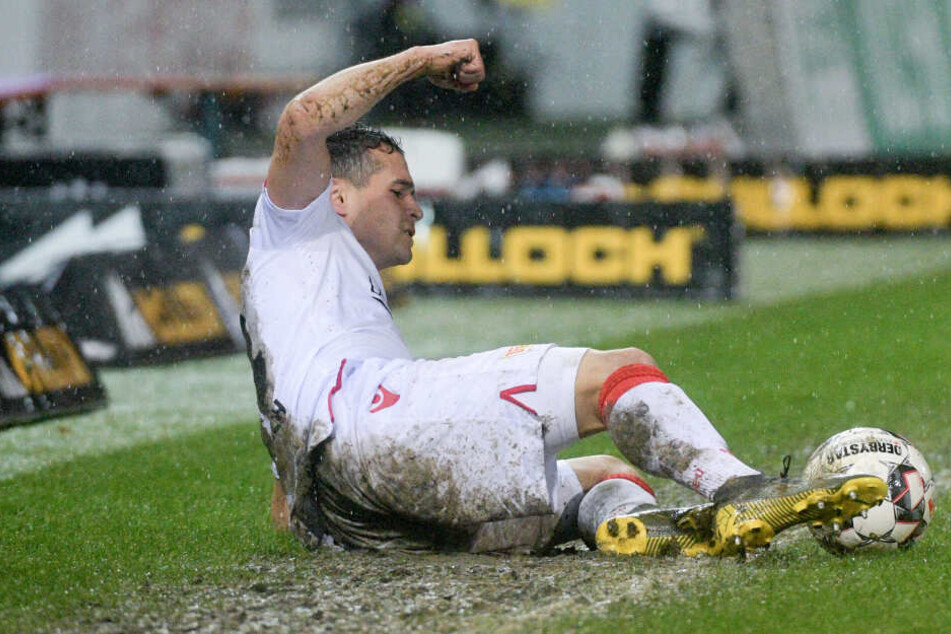 Manuel Schmiedebach vom 1. FC Union Berlin liegt im strömenden Regen im Matsch.